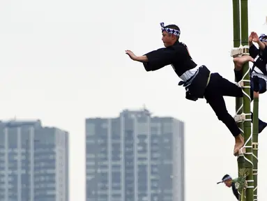 Para pemadam kebakaran berpakaian tradisonal menunjukan keahliannya menyeimbangkan tubuh di atas puncak bambu saat perayaan Tahun Baru di Tokyo, Jepang, Jumat (6/1). Atraksi ini mereka persembahkan untuk perayaan Tahun Baru. (Toshifumi KITAMURA/AFP)