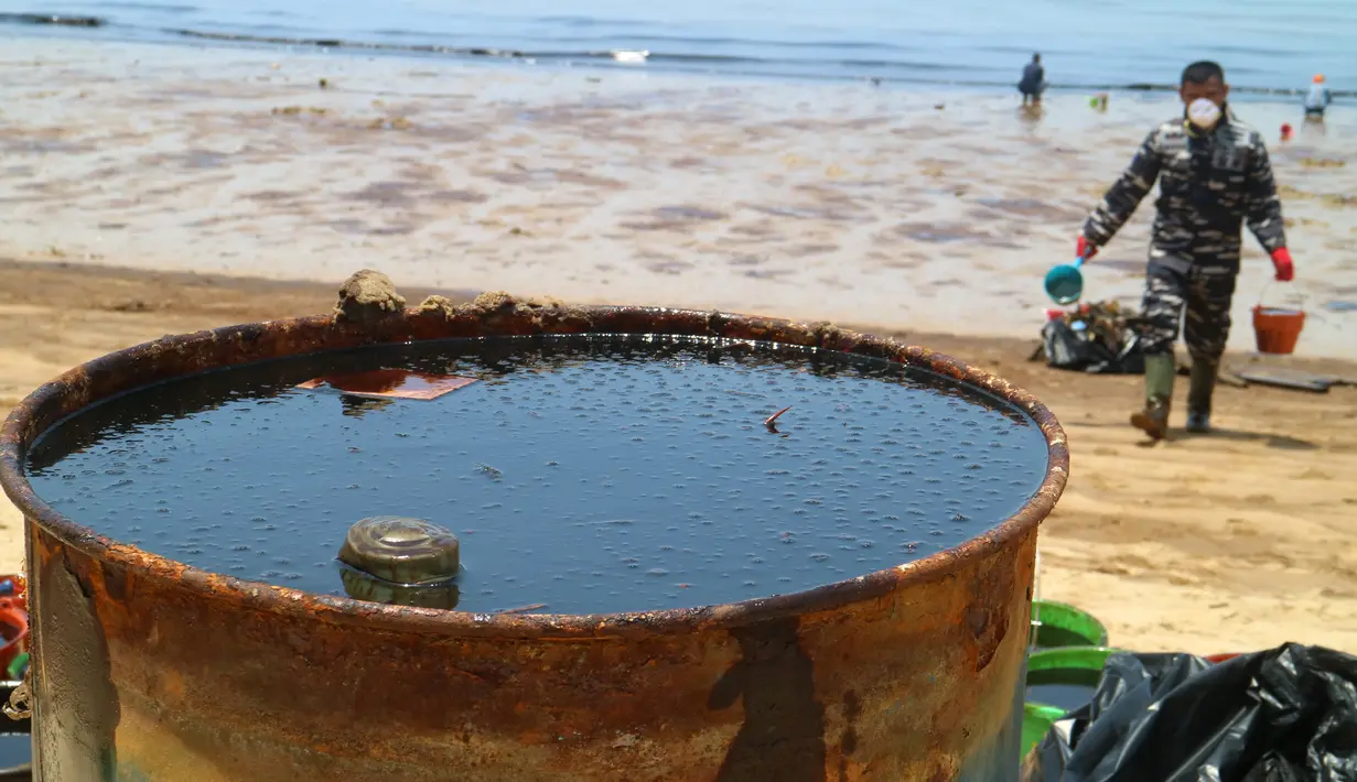 Petugas membersihkan Pantai Benua Patra setelah tumpahan minyak di sekitarnya, Balikpapan, Kalimantan Timur, Senin (2/4). Pembersihan pantai dilakukan secara manual agar lebih efektif untuk mengumpulkan ceceran minyak. (AFP)