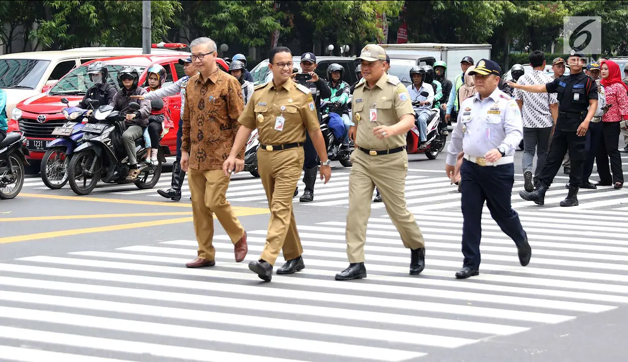 Gubernur DKI Jakarta Anies Baswedan (dua kiri) menyeberangi pelican crossing di Halte Transjakarta BI, Jakarta, Selasa (4/9). Pelican crossing diharap membuat warga memiliki kesempatan sama dalam menikmati layanan publik. (Liputan6.com/Immanuel Antonius)