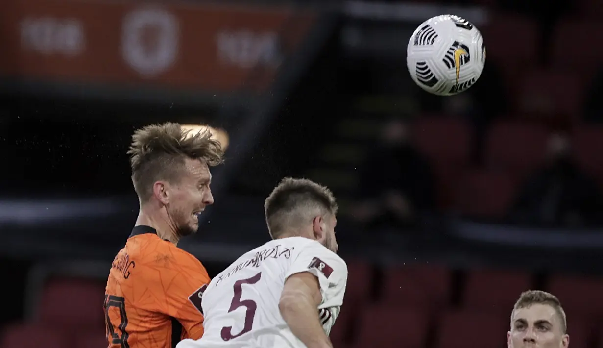 Gelandang Belanda, Luuk de Jong berebut bola udara dengan pemain Latvia, Antonijs Cernomiordijs dalam lanjutan Kualifikasi Piala Dunia 2022 zona Eropa Grup G di Johan Cruyff ArenA, Minggu (28/3/2021). Belanda menang atas Latvia 2-0. (AP Photo/Peter Dejong)
