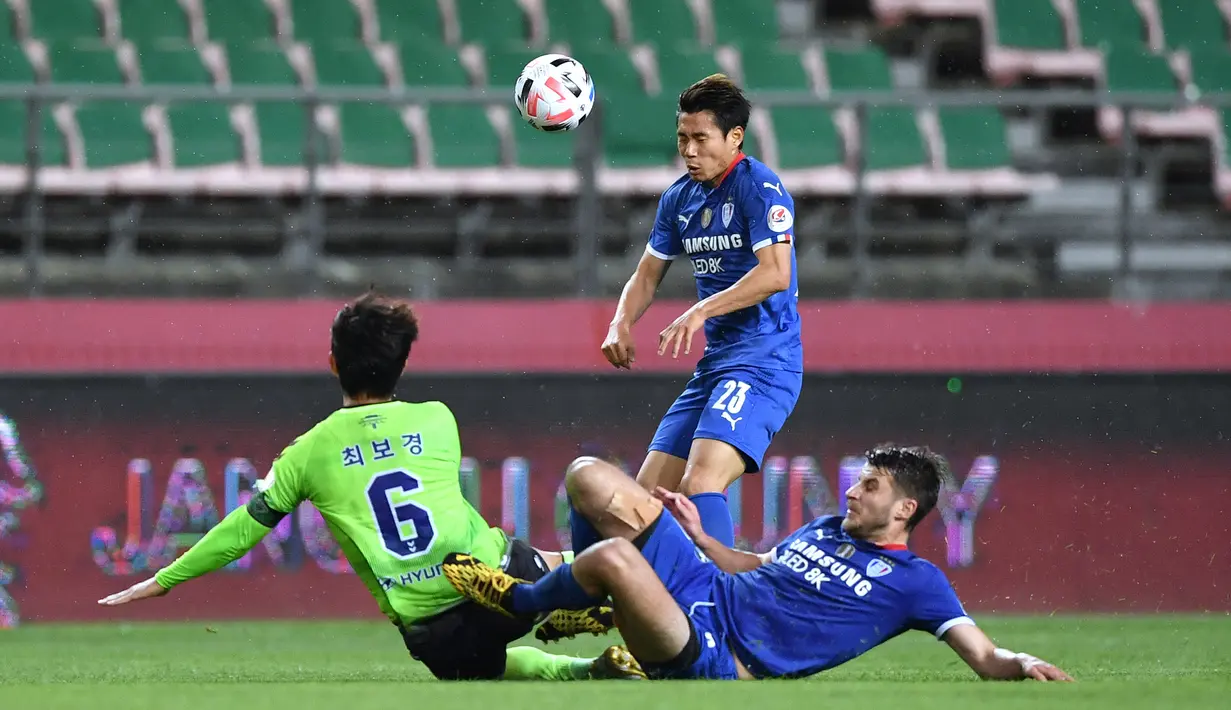 Pemain Jeonbuk Hyundai Motors berebut bola dengan pemain Suwon Samsung Blue Wings pada laga K-League Korea Selatan di Jeonju World Cup Stadium, Jeonju, Jumat (8/5/2020). Jeonbuk Hyundai Motors menang 1-0 atas Suwon Samsung Blue Wings. (AFP/Jung Yeon-Je)