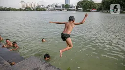 Seorang anak melompat di Danau Sunter, Jakarta, Selasa (2/2/2021). Minimnya lahan bermain anak membuat mereka memanfaatkan tempat yang tidak semestinya untuk bermain karena adanya risiko hanyut dan tenggelam bila tidak mampu untuk berenang. (Liputan6.com/Faizal Fanani)