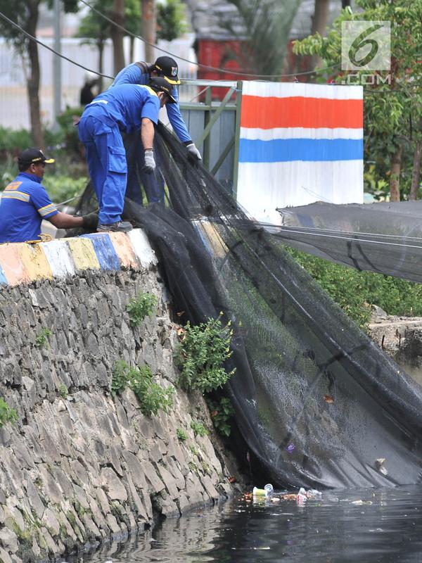 Petugas Dinas Sumber Daya Air Aliran Timur melepas kain waring atau jaring yang menutupi Kali Item di Kemayoran, Jakarta, Rabu (14/11). Pelepasan waring juga untuk mempermudah dalam membersihkan sampah di aliran Kali Item. (Merdeka.com/Iqbal S. Nugroho)
