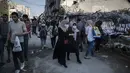 Orang-orang melintasi pedagang Palestina yang berjualan di samping puing-puing bangunan di Kota Gaza, Minggu (18/7/2021). Bagi warga Palestina yang kehilangan orang-orang terkasih dalam pertempuran antara militan Gaza dan Israel, tidak ada alasan untuk merayakan Idul Adha. (AP Photo/Khalil Hamra)
