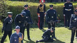 Seorang anggota The Rifles terjatuh menjelang pemakaman Pangeran Philip di luar Kapel St George di Kastil Windsor, Windsor, Inggris, Sabtu (17//4/2021). Seorang prajurit dekatnya berusaha menangkapnya saat rekannya jatuh. (Arthur Edwards/Pool via AP)