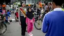 Seorang anak berfoto dengan polisi wanita (Polwan) dari kesatuan Samapta Bhayangkara (Sabhara) Polda Metro Jaya di kawasan Bundaran HI, Jakarta, Minggu (26/3). Polwan bersepeda ini memantau kelancaran car free day. (Liputan6.com/Faizal Fanani)