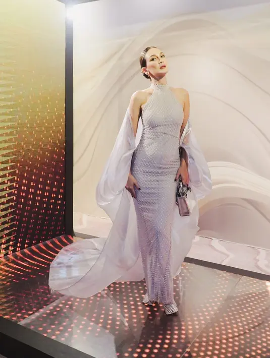 Pesona luar biasa Luna Maya dibalut dress silver yang berkilauan. Halter-neck dress dengan taburan kristal berkilauan membalut tubuhnya dengan amat apik, dipadukan mengenakan sheer outer dari lengan menjuntai hingga ke lantai. [Foto: Instagram/lunamaya]