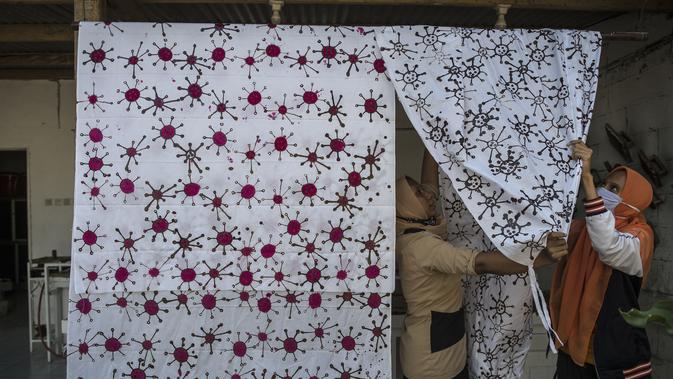 Penyandang disabilitas menjemur kain batik dengan motif virus corona di Surabaya, Jawa Timur (19/8/2020). Di tengah pandemi Covid-19, sekelompok penyandang disabilitas di Surabaya membuat batik bermotifkan virus corona. (AFP/JUNI KRISWANTO)