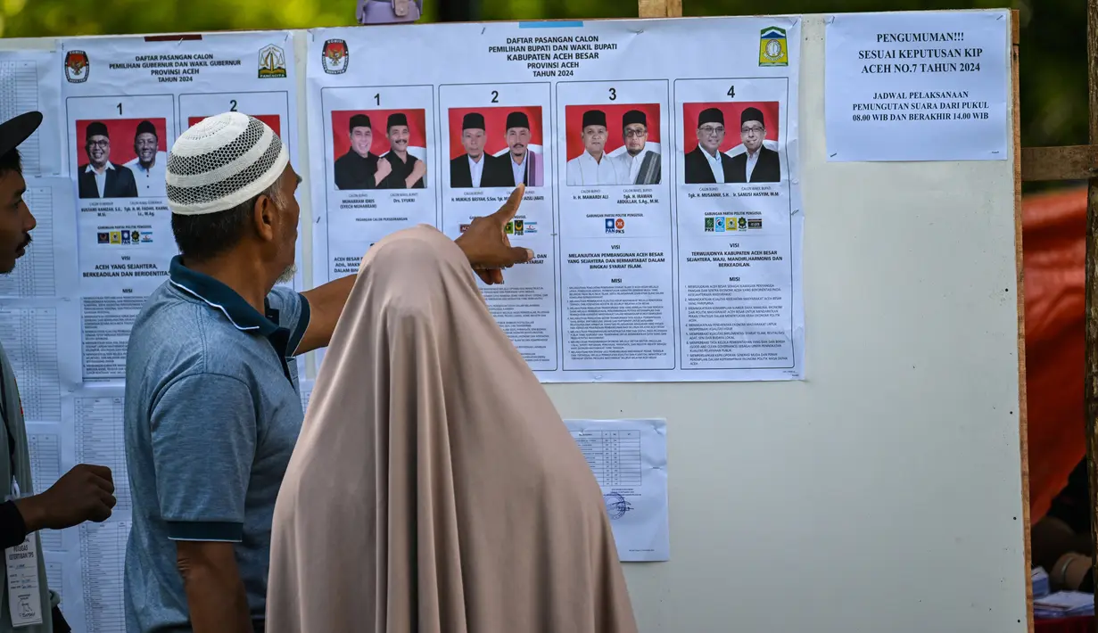 Melalui Pilkada, para pemimpin daerah yang dipilih langsung oleh rakyat diharapkan bekerja lebih maksimal dalam menjalankan tugas dan meningkatkan kesejahteraan masyarakat. Tampak dalam foto, calon pemilih memeriksa kandidat sebelum memberikan suara mereka dalam pemilihan eksekutif lokal di Darul Imarah, pinggiran Banda Aceh pada 27 November 2024. (CHAIDEER MAHYUDDIN/AFP)