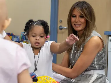Ibu Negara AS, Melania Trump bermain dengan pasien anak, Natalayah Fields saat mengunjungi Rumah Sakit Anak Monroe Carell Jr. di Nashville, Selasa (24/7). Kedatangan Melania untuk berdiskusi terkait Neonatal Abstinence Syndrome (NAS). (AFP/SAUL LOEB)