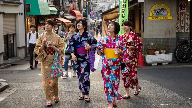 Sejumlah wanita memakai pakaian tradisional berjalan di sepanjang jalan perbelanjaan Yanaka Ginza di pusat Tokyo (30/9/2019). Bagian kota yang sudah tua ini terhindar dari pengeboman Sekutu selama Perang Dunia II dan selamat dari Gempa Besar Kanto dan Kebakaran tahun 1923. (AFP Photo/Odd Andersen)
