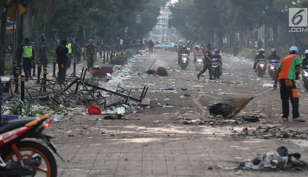 Petugas Penanganan Prasarana dan Sarana Umum (PPSU) atau Pasukan Oranye membersihkan sisa puing-puing pasca kerusuhan di kawasan Wahid Hasyim, Jakarta, Kamis (23/5/2019). Kerusuhan massa yang sebelumnya berdemo di depan gedung Bawaslu melebar ke Jalan Wahid Hasyim. (Liputan6.com/Herman Zakharia)