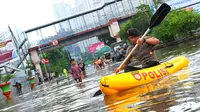 Seorang petugas polisi menggunakan perahu karet untuk melewati banjir yang menggenangi kawasan Grogol, Jakarta Barat, Rabu (11/2/2015). (Liputan6.com/Faisal R Syam)