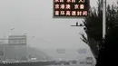 Suasana lalu lintas sebuah jalan yang diselimuti kabut asap tebal di Beijing, China (14/11). Pihak berwenang mengeluarkan peringatan kuning untuk polusi udara buruk pada hari Rabu. (AP Photo/Andy Wong)