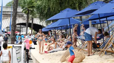 Warga bersantai dan berjemur di tepi sungai Seine pada hari pembukaan festival pantai Paris Plages, Paris, Prancis, (20/7). Meski baru-baru ini Prancis diserang banyak teror, warga tetap menyelenggarakan festival ini. (REUTERS / Charles Platiau)