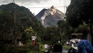 Orang-orang melihat Gunung Merapi yang memuntahkan batu dan abu di Yogyakarta (27/1/2021). BPPTKG menyatakan pada tanggal 27 Januari 2021 telah terjadi awan panas guguran di Gunung Merapi dengan jarak luncur maksimal 1200 meter ke arah hulu Sungai Krasak. (AFP/ Agung Supriyanto)