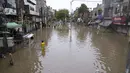 Orang-orang menyeberangi jalan yang tergenang air akibat hujan deras, di Lahore, Pakistan, Senin, 26 Juni 2023. (AP Photo/K.M. Chaudary)