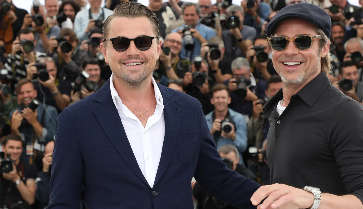 Aktor Brad Pitt dan Leonardo DiCaprio tersenyum saat berpose menghadiri pemutaran film 'Once Upon a Time in Hollywood' selama Festival Film Cannes Internasional ke-72 di Prancis (22/5/2019). (AP Photo/Vianney Le Caer)