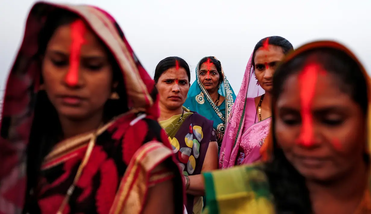 Sejumlah wanita melakukan ritual saat mengikuti festival keagamaan Chhat Puja di Mumbai, India (6/11). Ritual ini bentuk terima kasih mereka kepada Dewa Matahari  yang telah meberikan kehidupan. (Reuters/Danish Siddiqui)