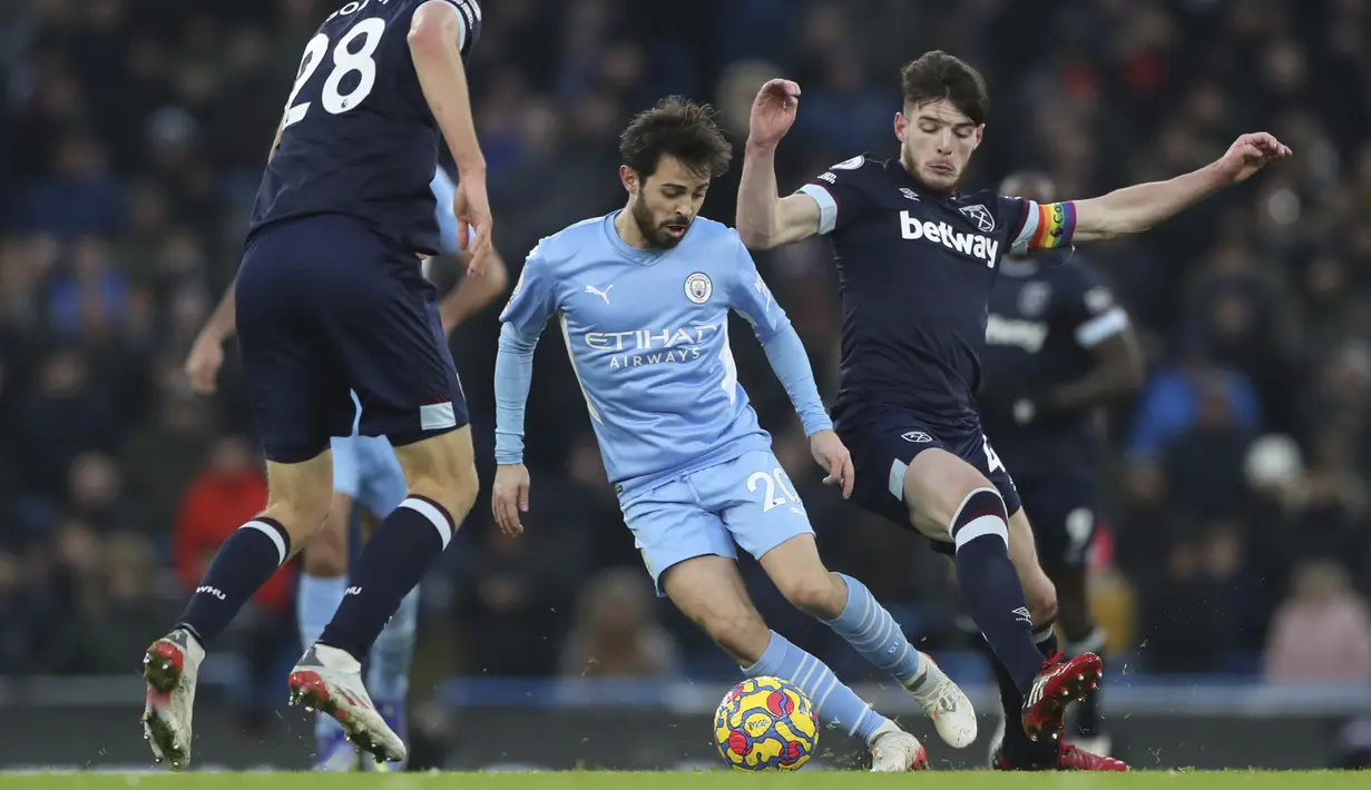 Gelandang Manchester City, Bernardo Silva membawa bola dari kawalan pemain West Ham United, Declan Rice pada pertandingan Liga Inggris di stadion Etihad, Inggris, Minggu (28/11/2021). Hasil Ini membawa Manchester City salip Liverpool di posisi dua klasemen Liga Inggris. (AP Photo/Scott Heppell)