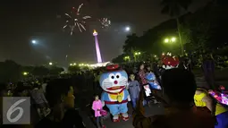 Warga saat menyaksikan pesta kembang api di kawasan Monas, Jakarta, Jumat (1/1). Antusiasme warga yang memadati Monas saat malam pergantian tahun membuat langit di kawasan tersebut dimeriahkan dengan pesta kembang api. (Liputan6.com/Immanuel Antonius)