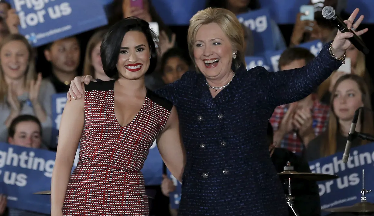 Calon presiden AS dari Partai Demokrat Hillary Clinton merangkul penyanyi Demi Lovato saat acara kampanye di Iowa City, Iowa, Amerika Serikat, (21/). Hillary menjadi satu-satunya perempuan yang mencalonkan diri menjadi Presiden AS. (REUTERS/Jim Muda)