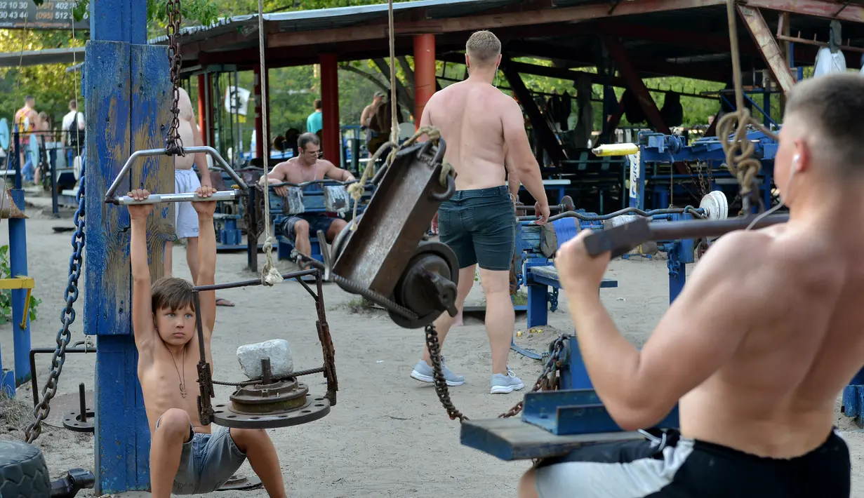 Aktivitas sejumlah orang melakukan latihan fitnes di sebuah gym outdoor di Ibu Kota Ukraina, Kiev, 18 Agustus 2017. Tanpa dipungut biaya, taman Kachalka menjadi tempat olahraga favorit pria di Kiev. (GENYA SAVILOV/AFP)
