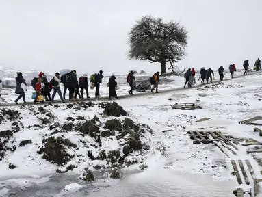 Sejumlah imigran berjalan melewati salju tebal membawa barang-barang mereka melintasi perbatasan Makedonia, dekat desa Miratovac, Serbia, (18/1/2016). (REUTERS/Marko Djurica)