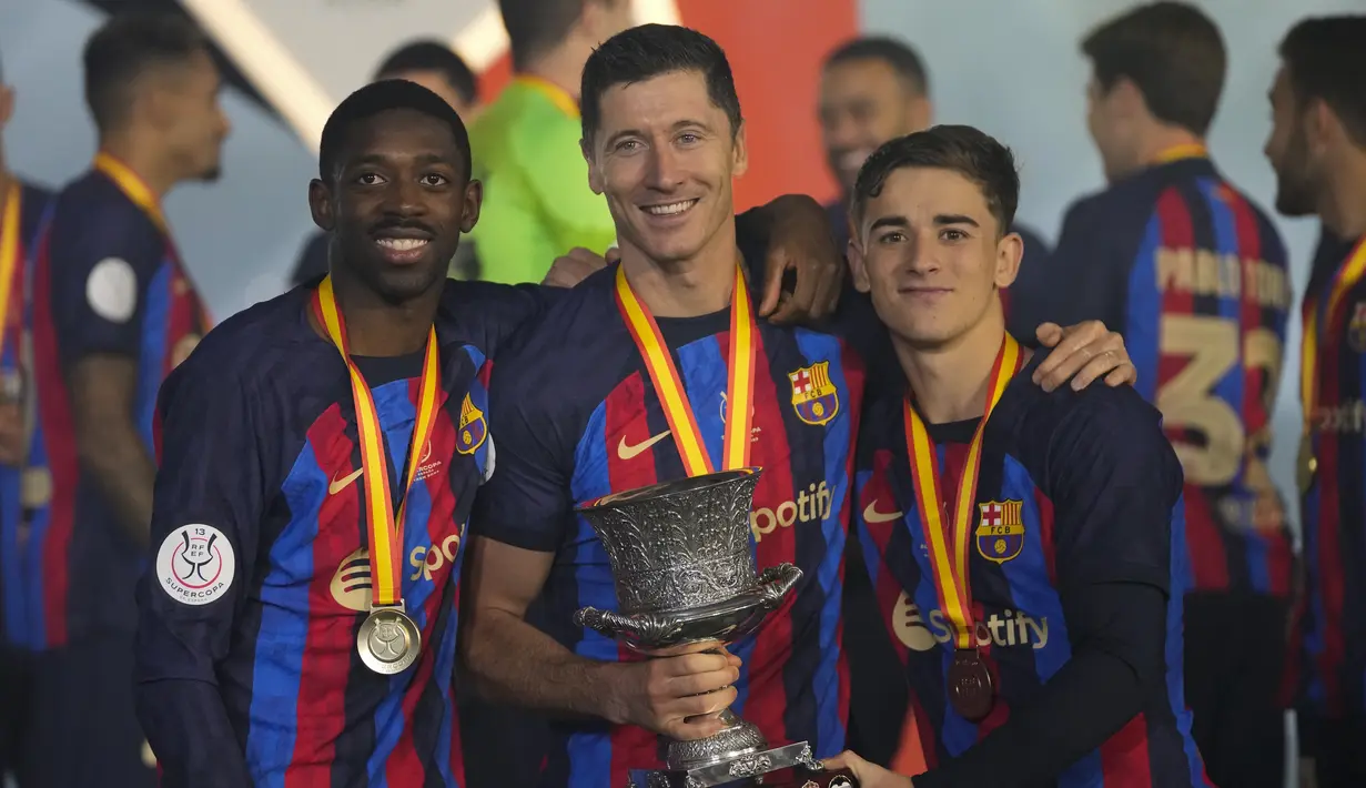 Para pemain Barcelona, Ousmane Dembele, Robert Lewandowski dan Gavi berpose dengan trofi usai menjuarai final Piala Super Spanyol di Stadion King Fahd, di Riyadh, Arab Saudi, Senin (16/1/2023). Trofi ini sekaligus menjadi trofi pertama Xavi Hernandez sebagai juru taktik Barcelona. (AP Photo/Hussein Malla)