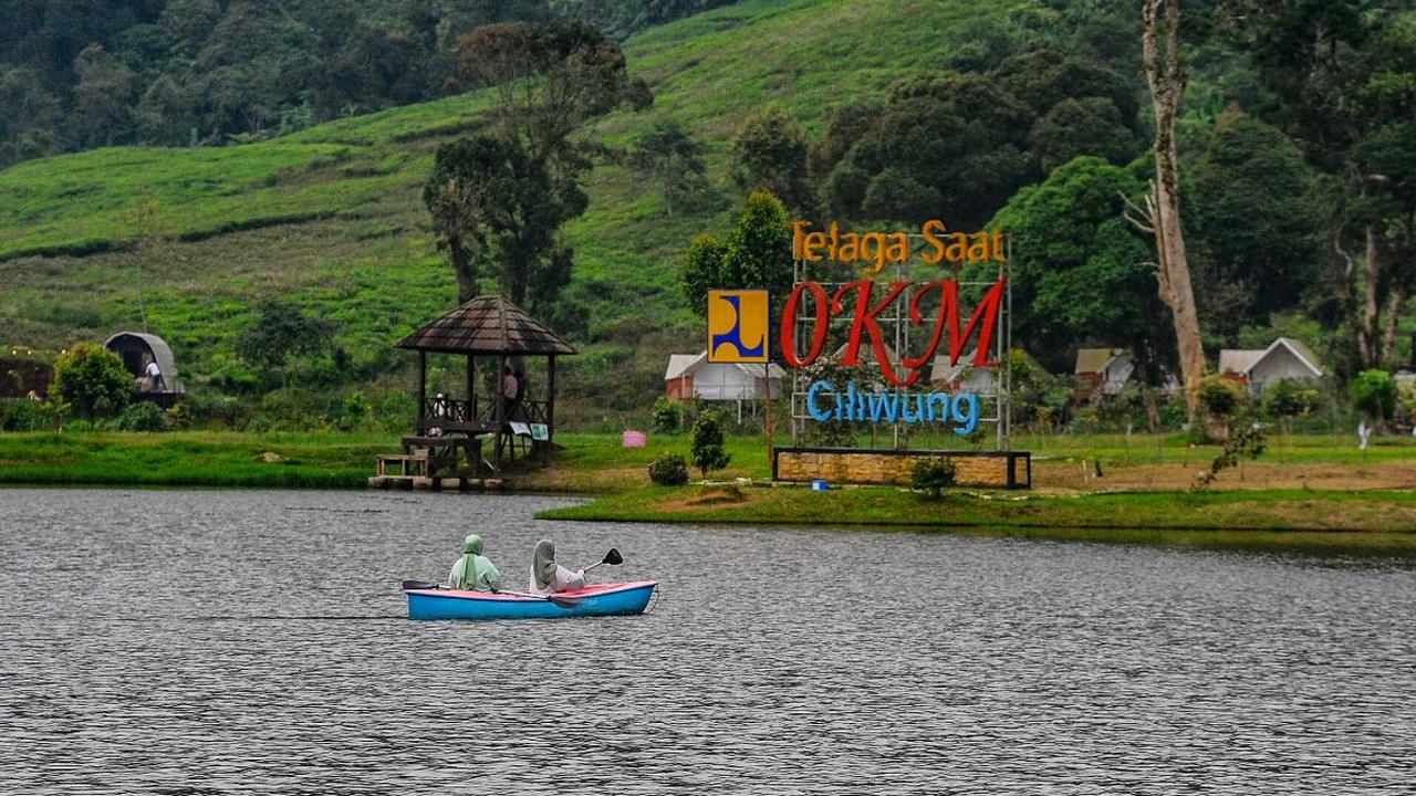 Pengunjung menaiki perahu saat menikmati keindahan Telaga Saat di kawasan Puncak, Bogor, Sabtu (1/6/2024). Telaga Saat, yang dikenal sebagai Titik 0 KM Ciliwung, merupakan hulu sungai yang menjadi sumber air minum utama warga Jakarta.&nbsp;Foto: Merdeka.c
