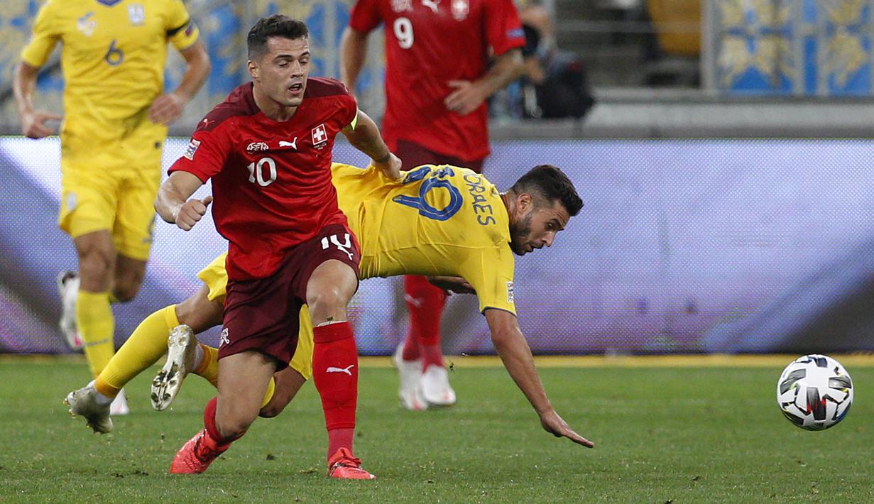 Gelandang Swiss, Granit Xhaka, berebut bola dengan penyerang Ukraina, Junior Moraes, pada laga Nations League di Stadion Arena Lviv, Jumat (4/9/2020) dini hari WIB. Ukraina menang 2-1 atas Swiss. (AFP/Anatolii Stepanov)