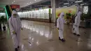 Sejumlah petugas berpakaian APD melakukan penyemprotan desinfektan pada lantai Pyongyang Department Store No1, di Pyongyang, Korea Utara, Senin (28/12/2020). (AFP/Kim Won Jin)