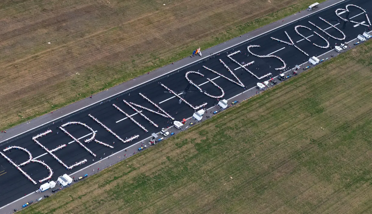 Pemandangan udara dari helikopter menunjukkan meja-meja yang ditata dalam bentuk pesan bertuliskan 'Berlin Loves You' (Berlin Mencintaimu) saat 3.000 warga menghadiri acara Berlin Freedom Dinner di landasan pacu bekas bandara Tegel di Berlin pada 7 Agustus 2021. (Christophe Gateau / DPA / AFP)