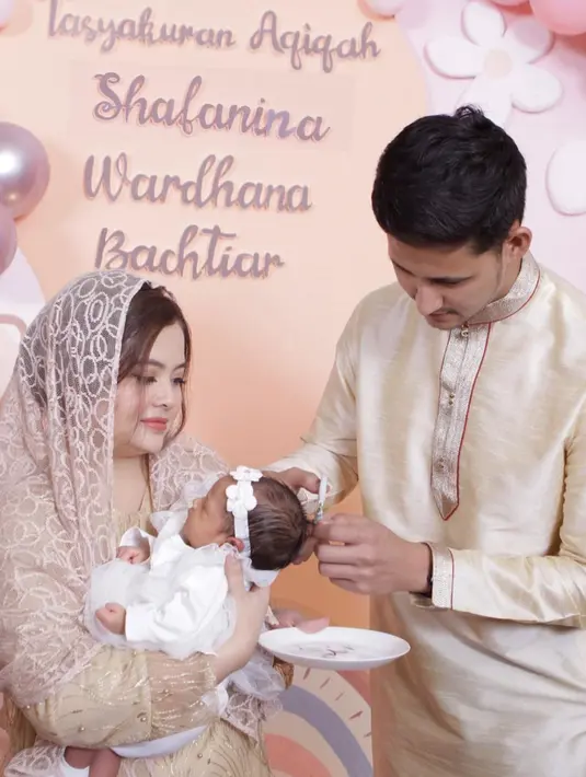 Anteng dalam gendongan sang bunda, ini adalah momen saat Randi Bachtiar mencukur rambut anak keduanya yang diabadikan dengan apik. Acara tasyakuran yang berlangsung khidmat ini dihadiri oleh keluarga dan kerabat dekat keduanya. Saat mencukur rambut Baby Shafa, Tasya dan Randi tampak fokus dan hati-hati. Meski foto candid sekalipun, Tasya Kamila tetap dipuji imut dan wajahnya tidak berubah sedari dulu. (Liputan6.com/IG/@tasyakamila)
