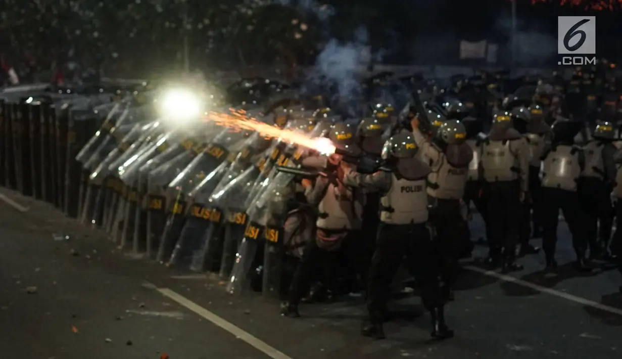 Aparat kepolisian berlindung di balik tameng saat massa aksi melemparkan petasan di sekitar Gedung DPR RI, Jakarta, Senin (30/9/2019). Buntut dari kerusuhan itu, aparat kepolisian melepaskan tembakan gas air mata guna membalas serangan petasan dari pengunjuk rasa. (Liputan6.com/Immanuel Antonius)
