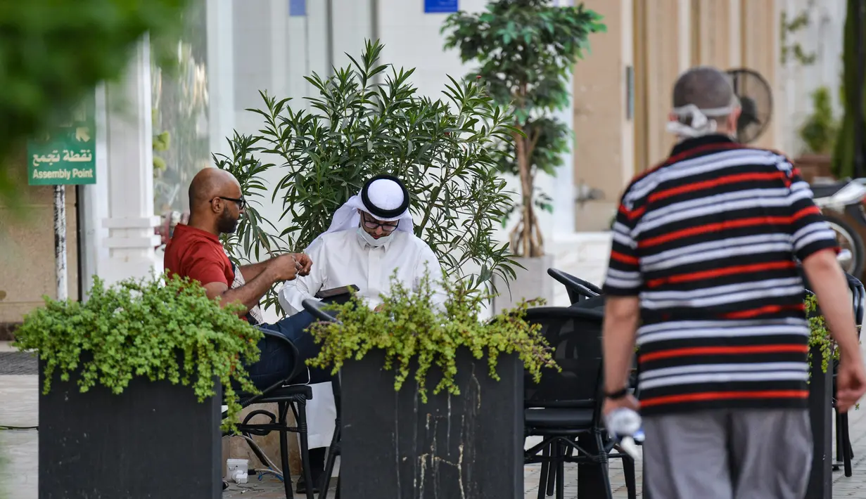 Sejumlah pria duduk di luar sebuah kafe di sepanjang jalan Tahlia di pusat ibukota Arab Saudi, Riyadh (21/6/2020). Pemerintah Arab Saudi mulai membuka kembali kegiatan perekonomian setelah melonggarkan lockdown Covid-19. (AFP Photo/Fayez Nureldine)
