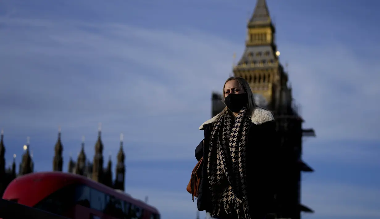 Seorang perempuan mengenakan masker saat melintasi Jembatan Westminster di London, Kamis (9/12/2021). Perdana Menteri Inggris Boris Johnson telah mengumumkan pembatasan yang lebih ketat untuk membendung penyebaran varian baru Covid-19, omicron. (AP Photo/Frank Augstein)