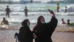 Wanita Palestina berselfie selama liburan Idul Fitri, di pantai laut Mediterania di Tel Aviv, Israel (25/5/2020).  Idul Fitri menandai akhir bulan suci Ramadhan, perayaan tiga hari yang biasanya menggembirakan telah berkurang secara signifikan karena pandemi coronavirus. (AP Photo/Oded Balilty)