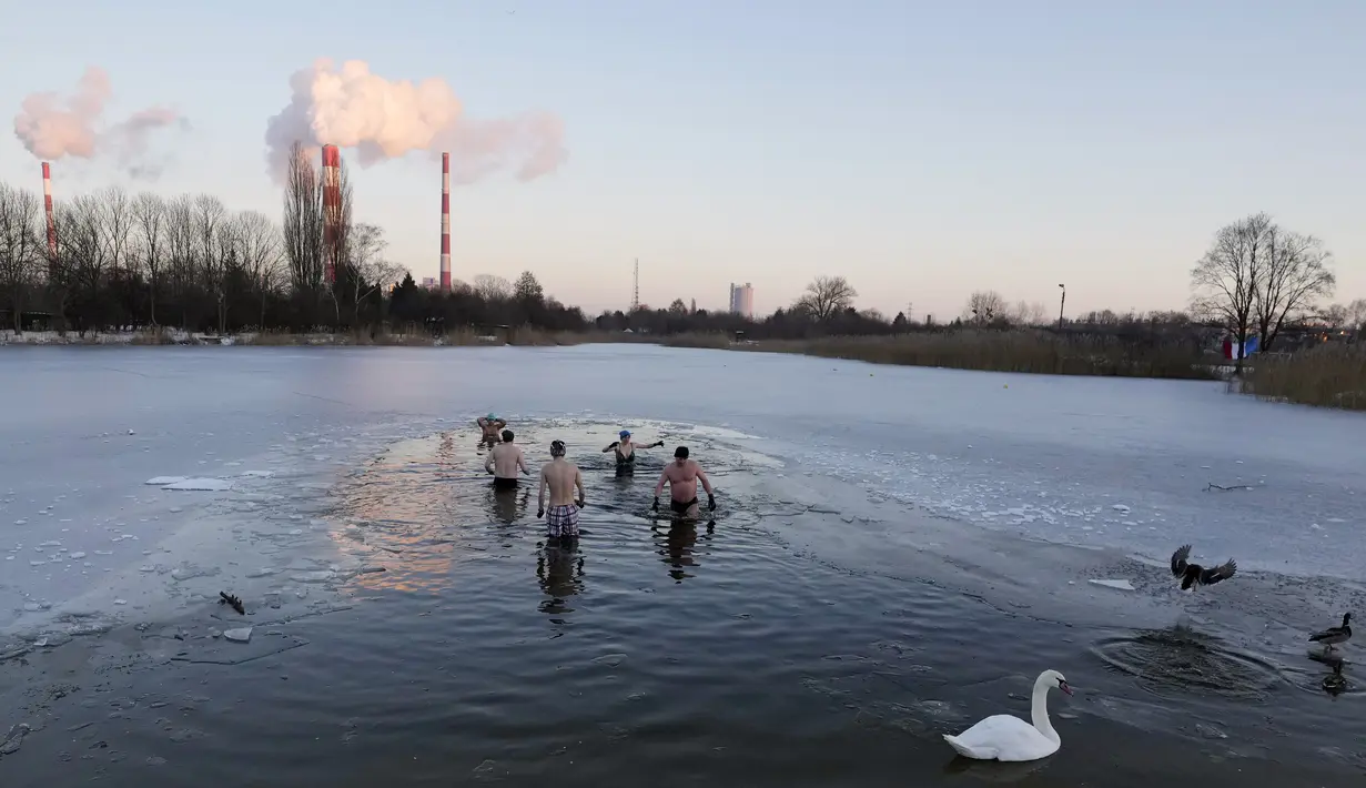 Orang-orang berenang di danau dengan suhu di bawah titik beku di Warsawa, Polandia (26/12/2021). Iklim di Polandia pada musim dingin yang sangat dingin, seringkali di bawah titik beku (0 °C atau 32 °F), dan musim panas yang hangat.  (AP Photo/Czarek Sokolowski)