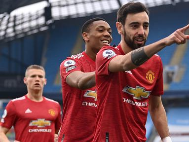 Gelandang Manchester United, Bruno Fernandes (depan) melakukan selebrasi usai mencetak gol pertama timnya ke gawang Manchester City melalui eksekusi penalti dalam laga lanjutan Liga Inggris 2020/21 di Etihad Stadium, Minggu (7/3/2021). MU menang 2-0 atas Mancity. (AFP/Laurence Griffiths/Pool)
