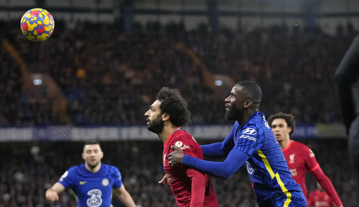 Penyerang Liverpool Mohamed Salah berebut bola dengan bek Chelsea Antonio Rudiger pada pekan ke-21 Liga Inggris di Stamford Bridge, London, Minggu (2/1/2022) malam WIB. Duel Chelsea vs Liverpool berakhir imbang dengan skor akhir 2-2. (AP Photo/Matt Dunham)