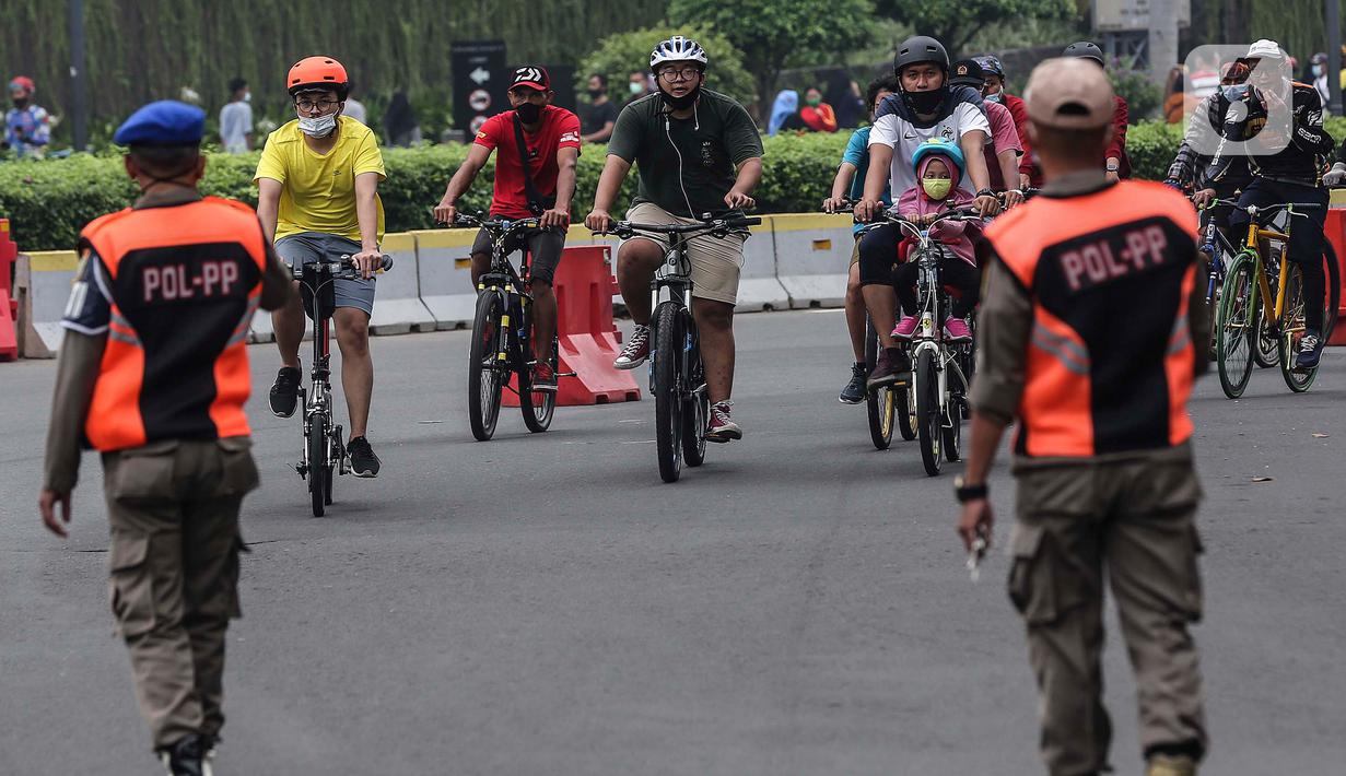 Satpol PP saat mengawasi penggunaan masker terhadap warga yang berolahraga di kawasan Bundaran HI, Jakarta, Minggu (17/1/2021). Sosialisasi penggunaan masker untuk mencegah penularan virus corona COVID-19 masih saja diabaikan karena rendahnya kesadaran masyarakat. (Liputan6.com/Johan Tallo)