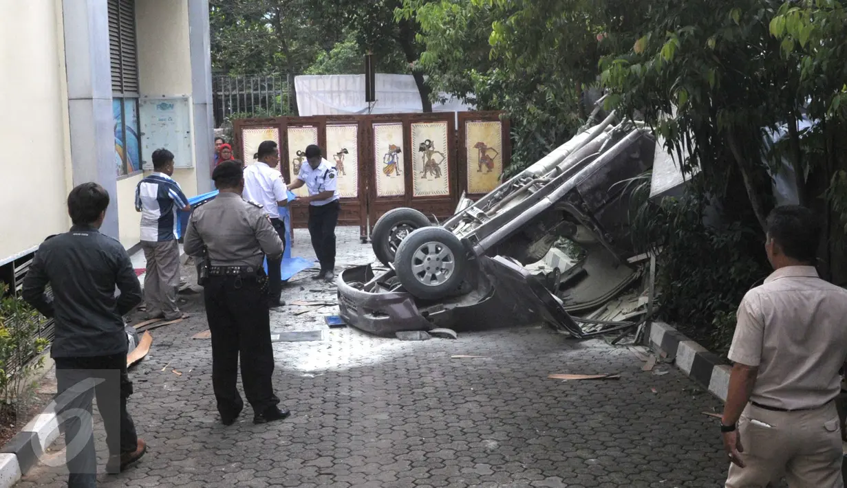 Petugas saat akan menutupi sebuah mobil Toyota Kijang warna merah marun yang jatuh dari lantai 3 Gedung Migas, Jakarta, Selasa (5/4). Mobil itu menabrak dinding pembatas di lantai 3 dan kemudian jatuh terbalik. (Liputan6.com/Helmi Affandi)