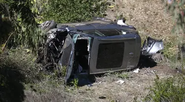 Sebuah crane digunakan untuk mengangkat mobil pegolf Tiger Woods setelah kecelakaan di Rancho Palos Verdes, California, pinggiran Los Angeles, Selasa (23/2/2021). Kendaraan yang dibawa Woods keluar dari jalan raya dan terguling ke lereng sebelum berhenti di dasar jurang. (AP Photo/Mark J. Terrill)