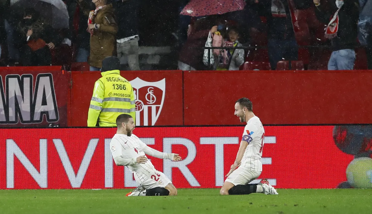 Gelandang Sevilla, Papu Gomez (kiri) berselebrasi dengan rekannya Ivan Rakitic usai mencetak gol ke gawang Barcelona pada pertandingan La Liga Spanyol di stadion Ramon Sanchez-Pizjuan, Spanyol, Rabu (22/12/2021). Sevilla kini berada di urutan kedua dengan 38 poin. (AP Photo/Angel Fernandez)