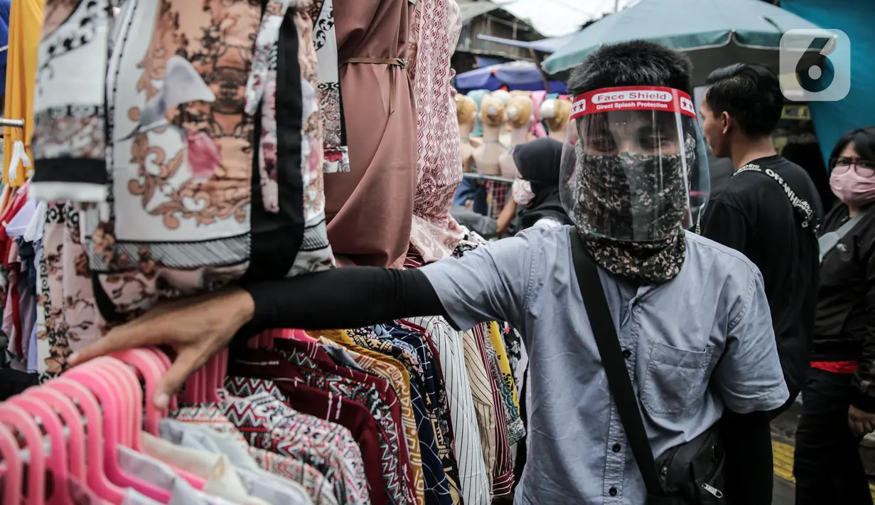 Pedagang menggunakan alat pelindung wajah (Face Shield) saat berjualan di Kawasan Tanah Abang, Jakarta, Senin (18/5/2020). Penggunaan alat pelindung wajah itu sebagai upaya untuk melindungi diri saat berhubungan dengan pembeli dalam pecegahan penyebaran COVID-19. (Liputan6.com/Faizal Fanani)