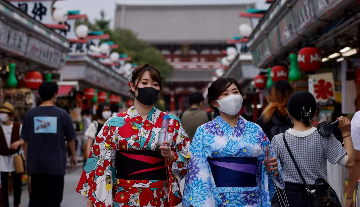 Dua wanita mengenakan yukata, pakaian musim panas tradisional Jepang mengunjungi kuil Buddha Sensoji di distrik Asakusa Tokyo (12/8/2021). Wanita biasanya mengenakan yukata dari bahan berwarna dasar cerah atau warna pastel dengan corak aneka warna yang terang. (AFP/David Gannon)