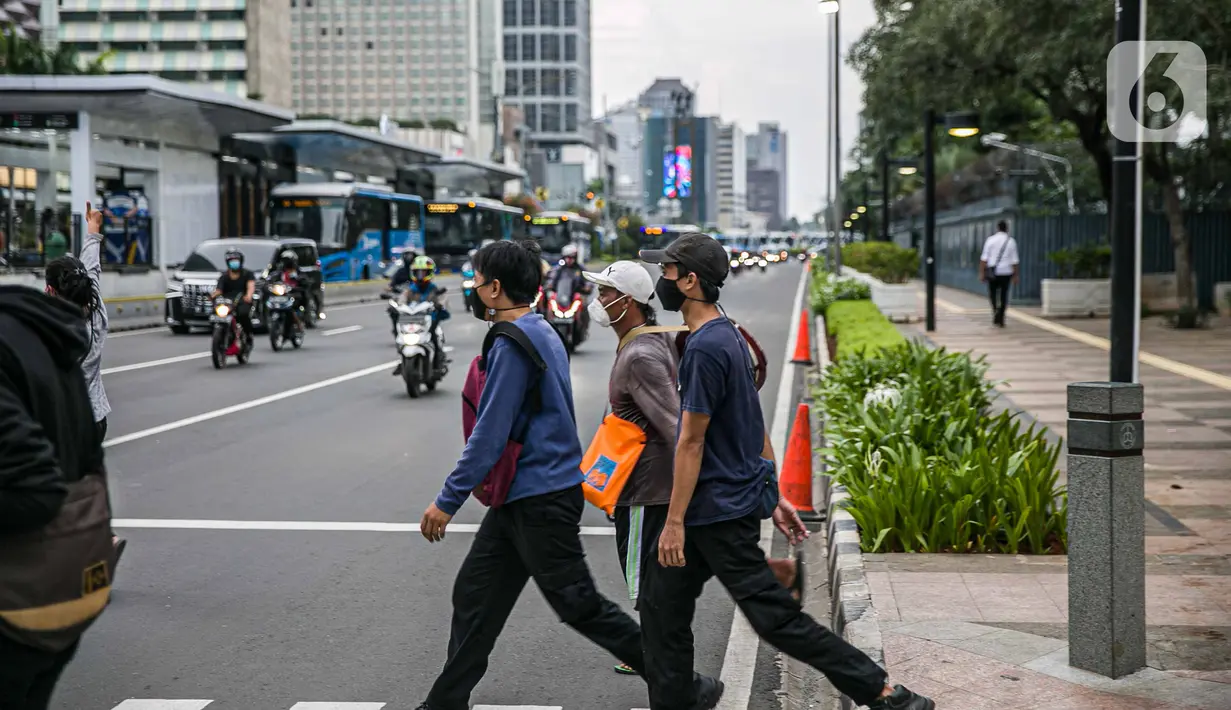 Pejalan kaki menyeberang jalan di kawasan Sudirman, Jakarta Pusat, Rabu (6/1/2021). Pemerintah memberlakukan kebijakan pembatasan sosial berskala besar (PSBB) di wilayah Jawa dan Bali mulai 11 hingga 25 Januari 2021 menyusul lonjakan kasus Covid-19 di sejumlah daerah. (Liputan6.com/Faizal Fanani)