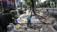 Pekerja menyelesaikan proyek revitalisasi trotoar di Jalan Medan Merdeka Selatan, Jakarta Pusat, Selasa (22/11/2022). Pemprov DKI Jakarta mengalokasikan anggaran sebesar Rp 171 miliar dalam Rancangan Anggaran Pendapatan dan Belanja Daerah (RAPBD) DKI Jakarta 2023 untuk revitalisasi trotoar di Ibu Kota. (merdeka.com/Iqbal S. Nugroho)