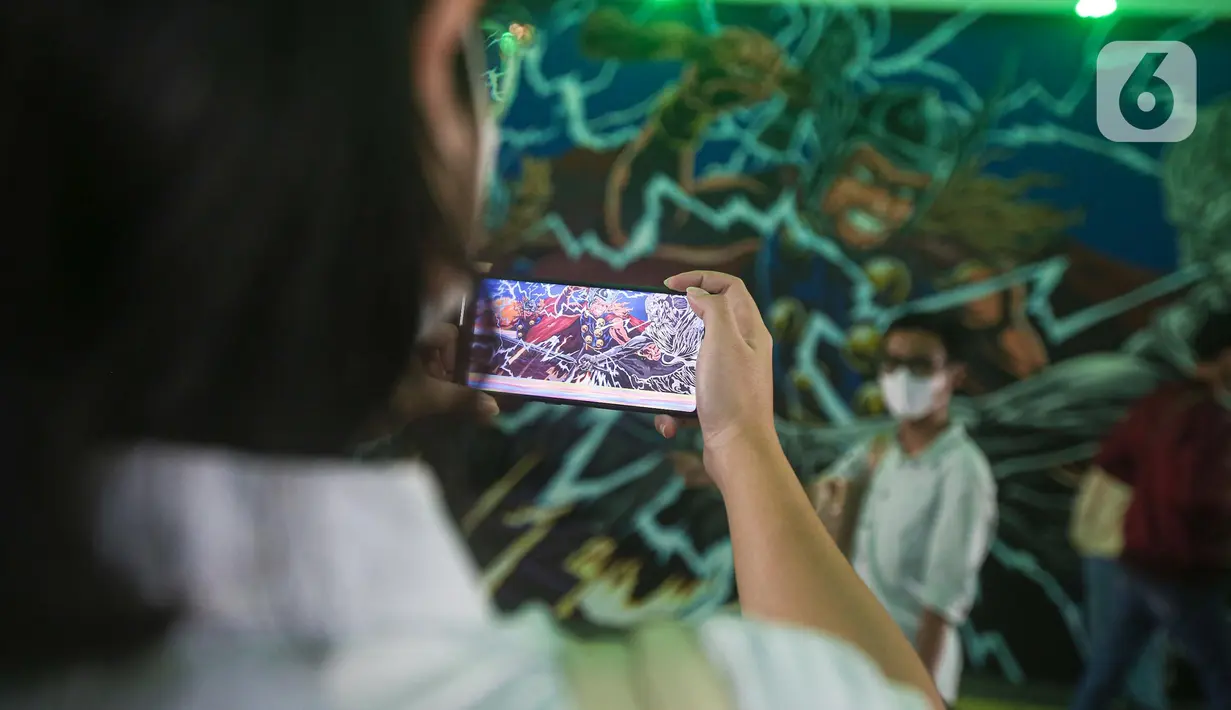 Warga berpose dengan latar belakang mural kolaborasi di Terowongan Kendal, Kawasan TOD Dukuh Atas, Jakarta, Rabu (6/7/2022). Karya seni mural yang terinspirasi dari film Marvel Studios "Thor: Love and Thunder" itu memanfaatkan teknologi augmented reality (AR). (Liputan6.com/Faizal Fanani)